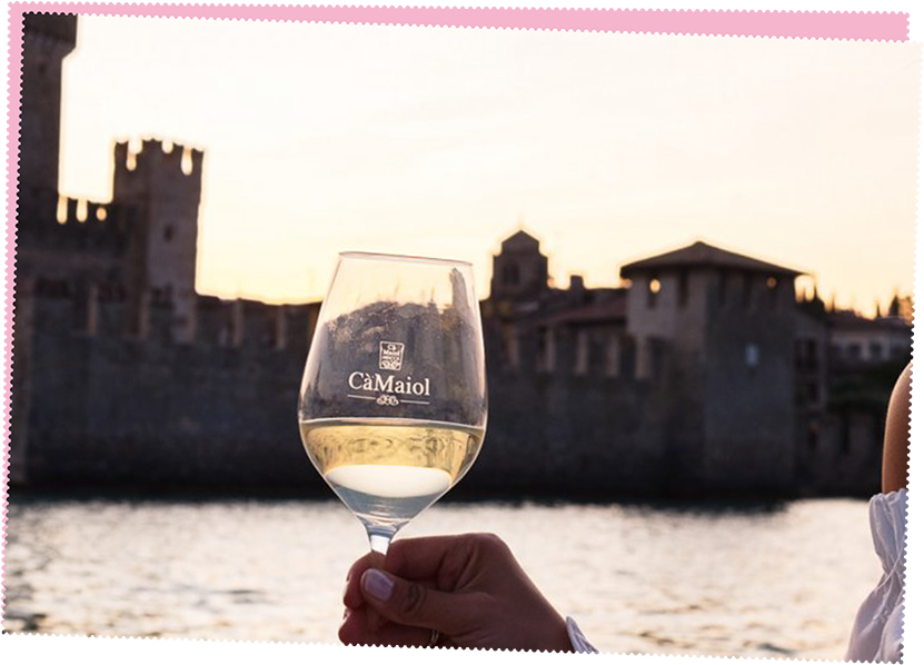 Person holding a glass of wine next to a city river